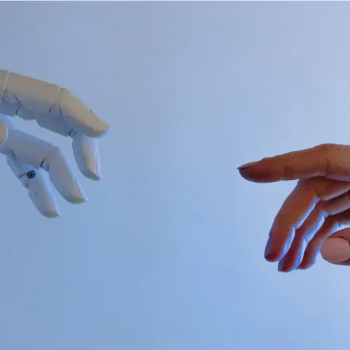 A robotic hand reaching toward a human hand, symbolizing the balance between automation and manual outreach in link-building services.